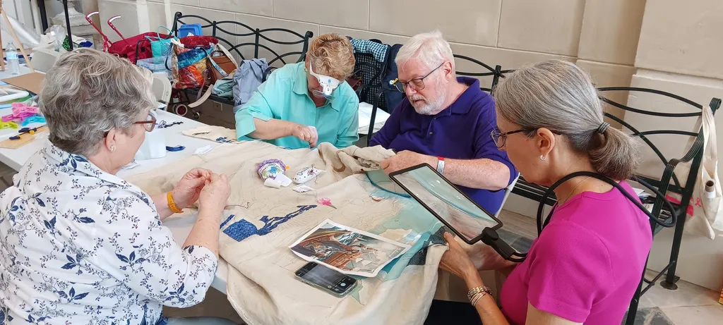 Delaware volunteers Joan and Tom stitch with newcomers Gloria and Geni on the state panel at Winterthur.